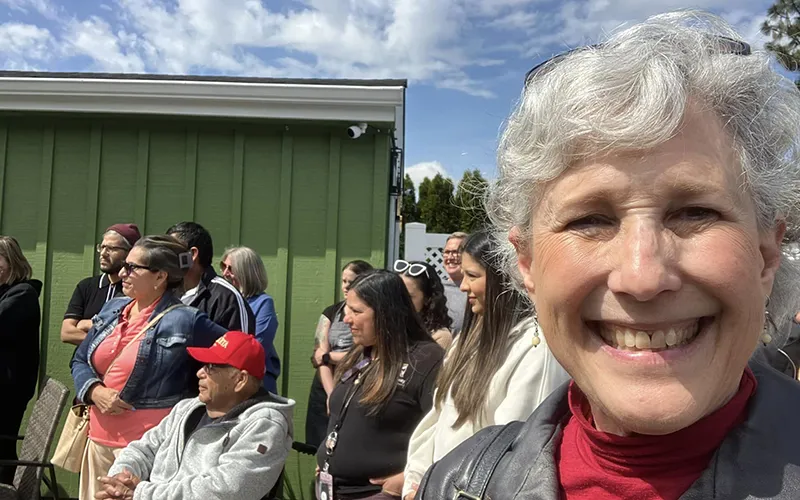 Ribbon cutting at bridgeway - Cathy Clark smiling with a crowd behind her